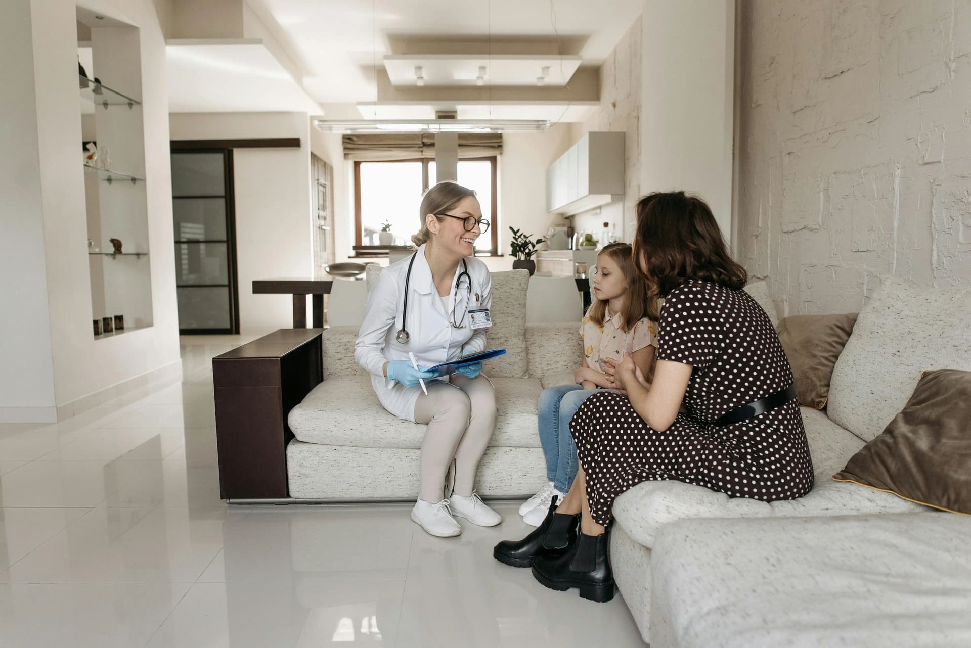 A doctor visiting a mother and daughter on the sofa in their living room
